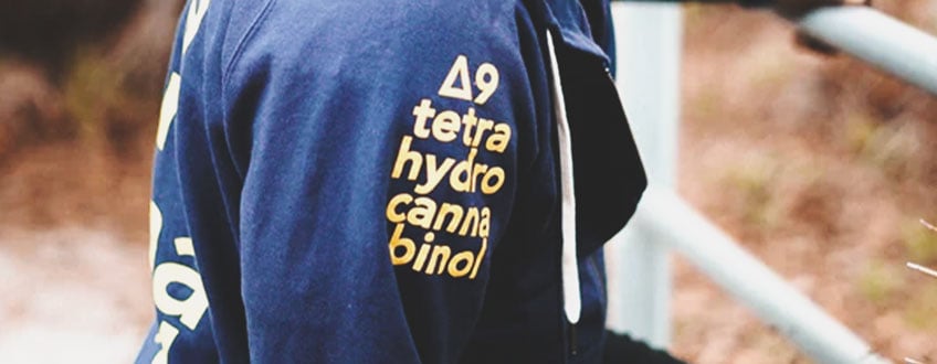 Een blauwe hoodie met de chemische formule voor THC op de mouw gedrukt.
