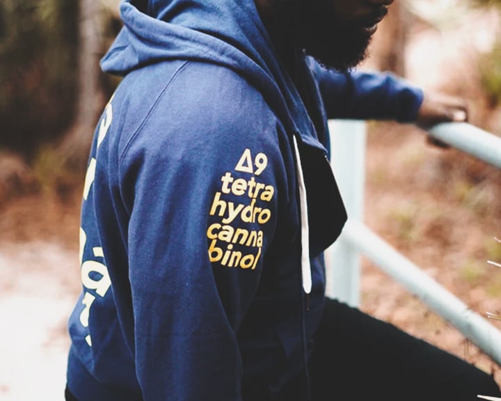 Een blauwe hoodie met de chemische formule voor THC op de mouw gedrukt.