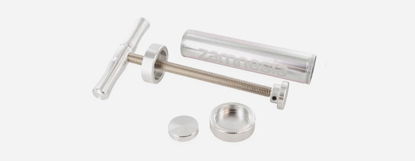 Een zilveren metalen spuit met een handvat en een zuiger.