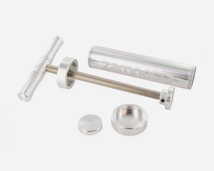 Een zilveren metalen spuit met een handvat en een zuiger.