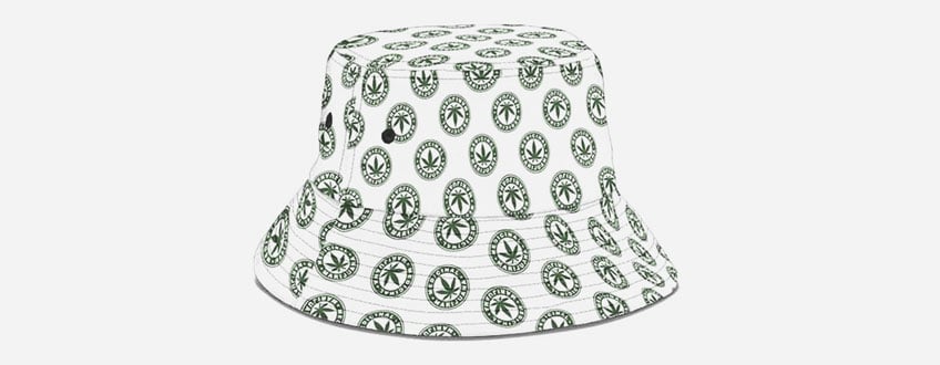 Een witte bucket hat met een patroon van groene marihuanabladeren.