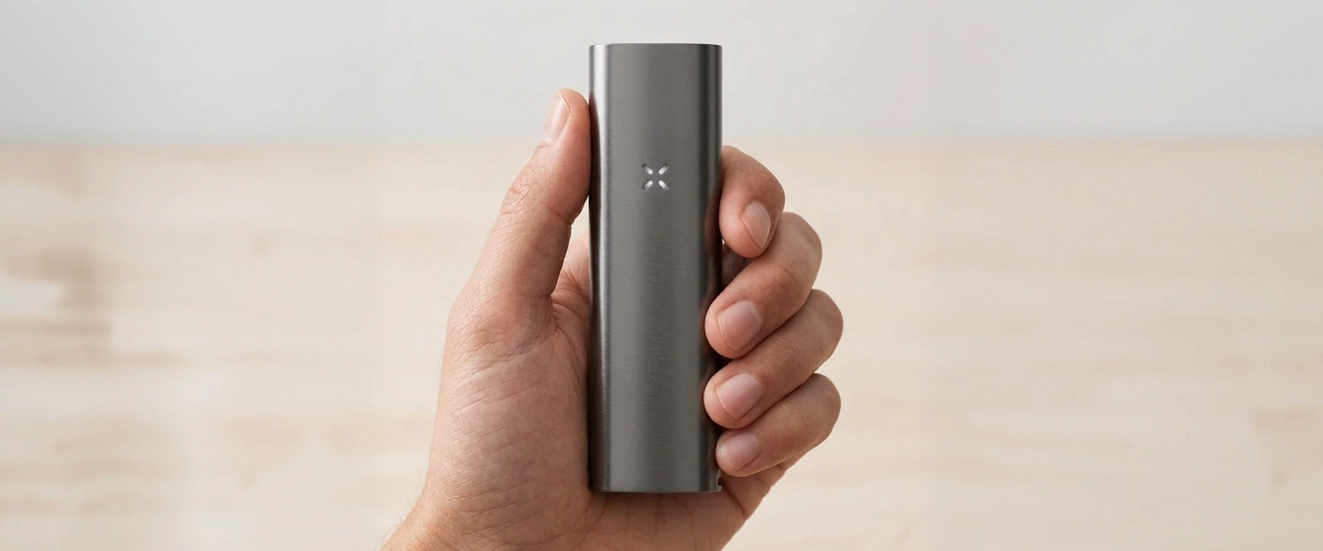 PAX Four vaporizer vastgehouden in één hand, met zijn slanke matte behuizing, compacte formaat en led-bloembladindicator aan de voorkant